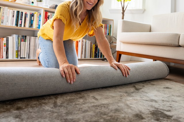 An image of a woman rolling a gray rug