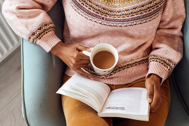 An image of a woman sitting in a chair with a cup of coffee and a book