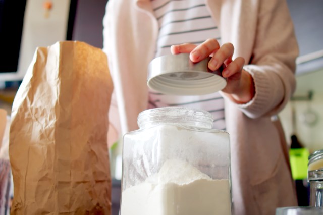 An image of a woman putting the lid on a canister of flour