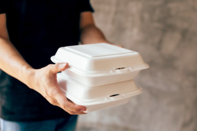 An image of a man carrying two styrofoam containers