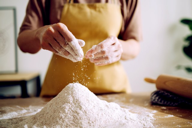 An image of a person in an apron with a pile of flour in front of them