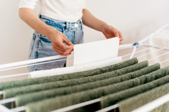 An image of a woman putting clothes on a drying rack