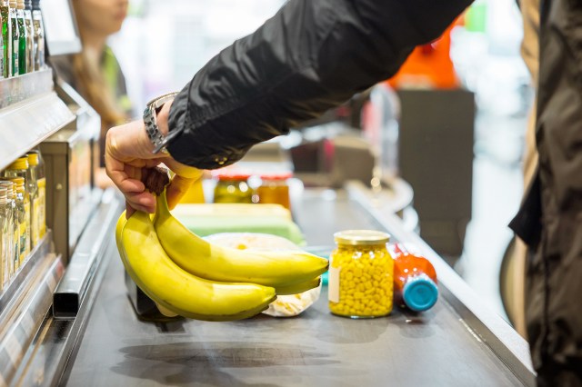 An image of a person putting grocery on a register belt