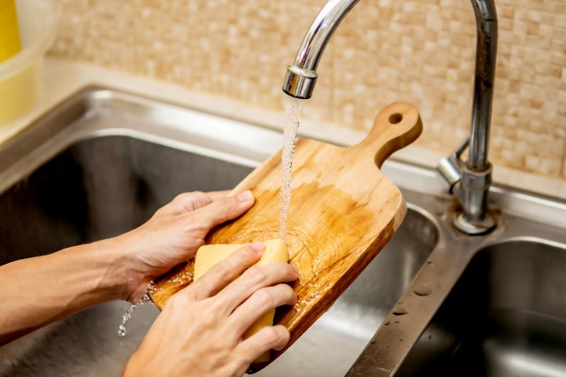 An image of a person washing a wooden cutting board