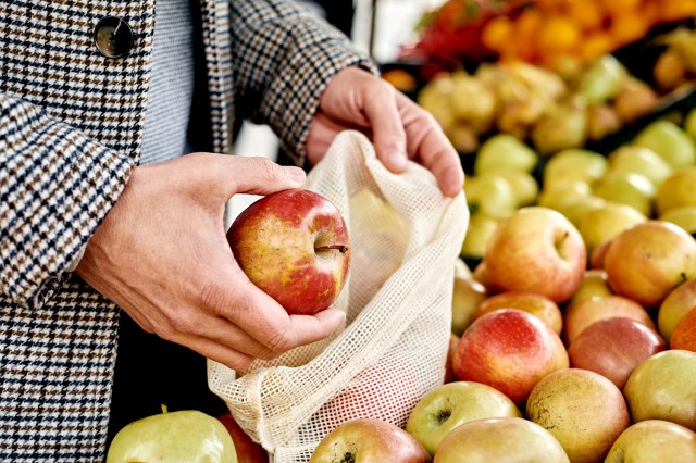 An image of a person in the produce section putting an apple into a bag