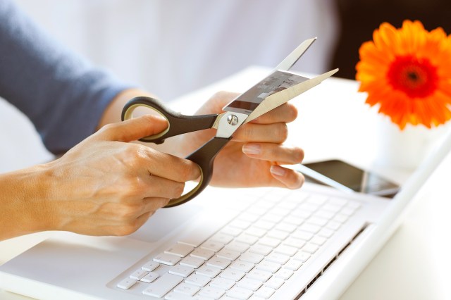 An image of a person cutting a credit card with scissors