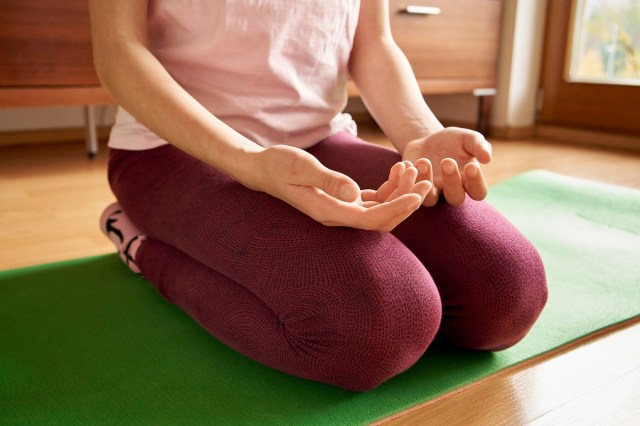 An image of a woman sitting on her knees on a yoga mat