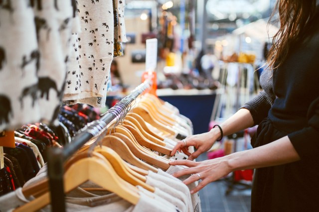 An image of a woman looking through a clothing rack