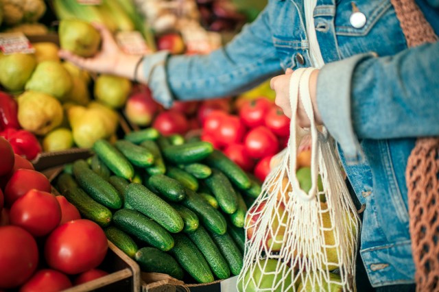 An image of a woman picking out vegetables at a grocery store