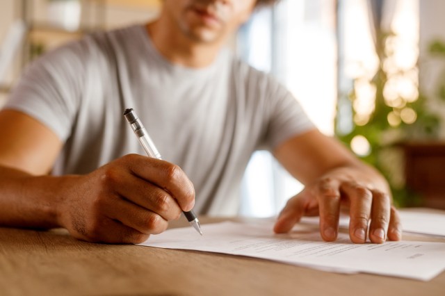 An image of a man signing a document