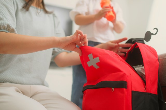 An image of a woman opening a red emergency backpack