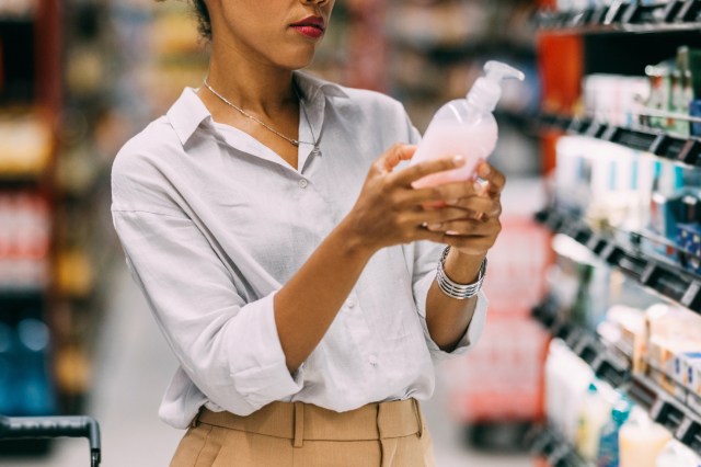 An image of a woman looking at a bottle of soap