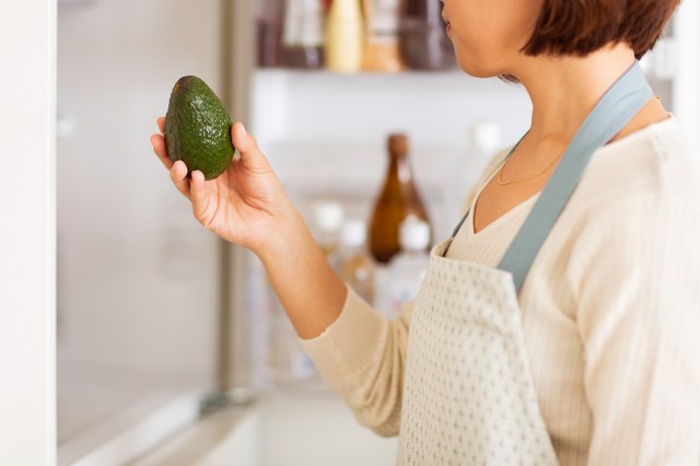 An image of a woman holding an avocado