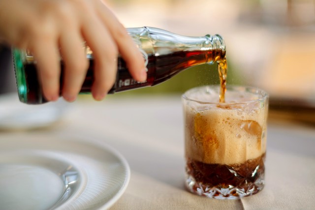 An image of a person pouring a glass of cola