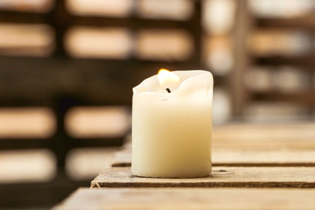 A lit candle on a wooden table