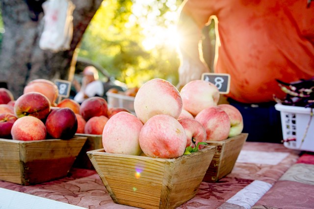 An image of peaches on a table at a farmer's market