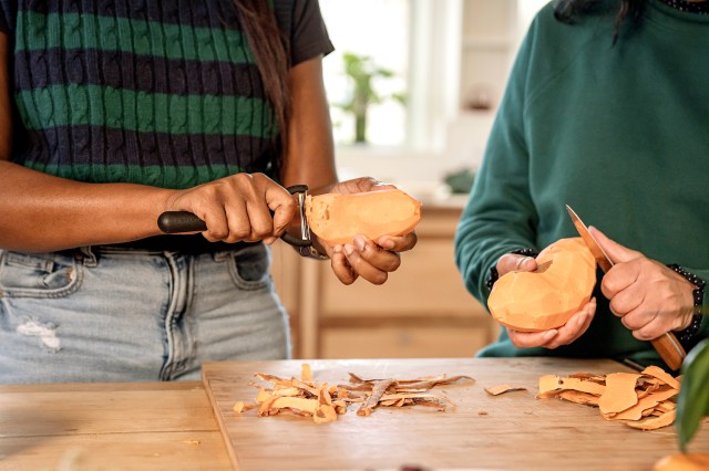 An image of two women peeling sweet potatoes