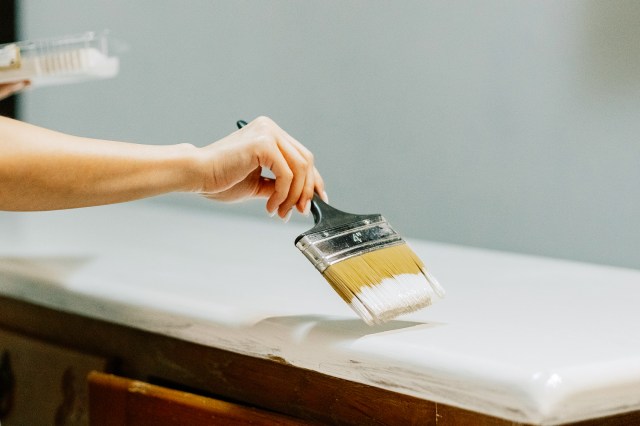 A hand paints a countertop white