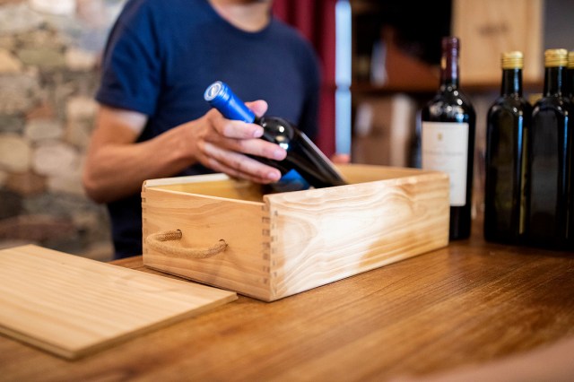 An image of a person taking a bottle of wine out of a wooden crate