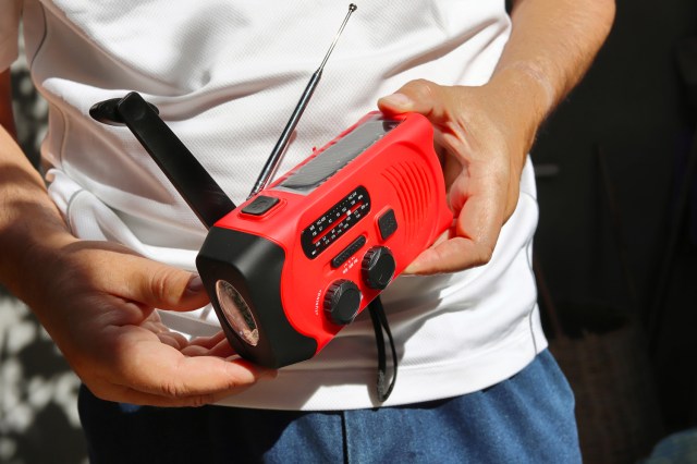 An image of a man holding a red emergency radio