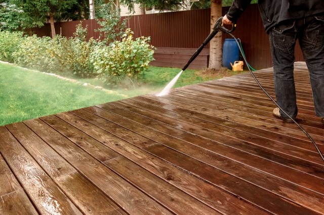 An image of a person power washing a deck