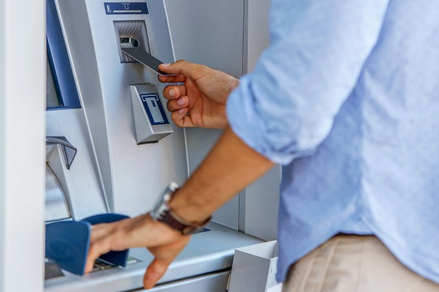 An image of a man putting a card into an ATM