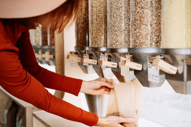 An image of a woman putting seeds into a bag from a dispenser 