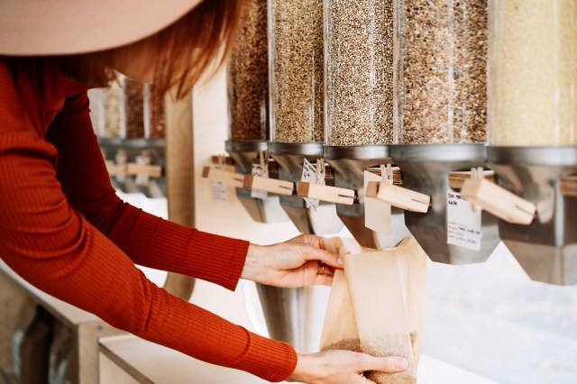 An image of a woman putting seeds into a bag from a dispenser