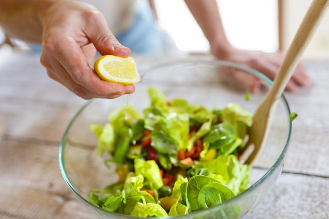 An image of a person squeezing lemon onto a salad