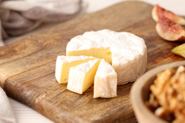 An image of brie cheese on a wooden cutting board