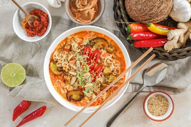 An image of a bowl of ramen and several bowls of condiments