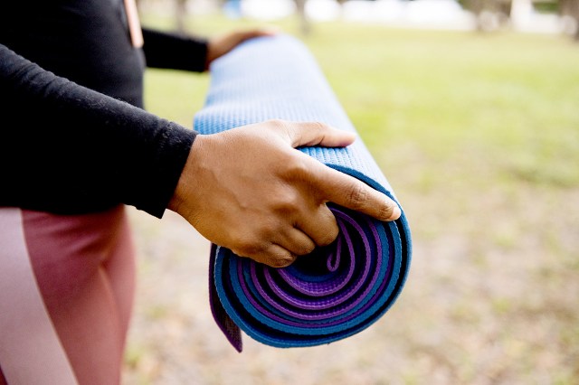 An image of a woman holding a blue yoga mat
