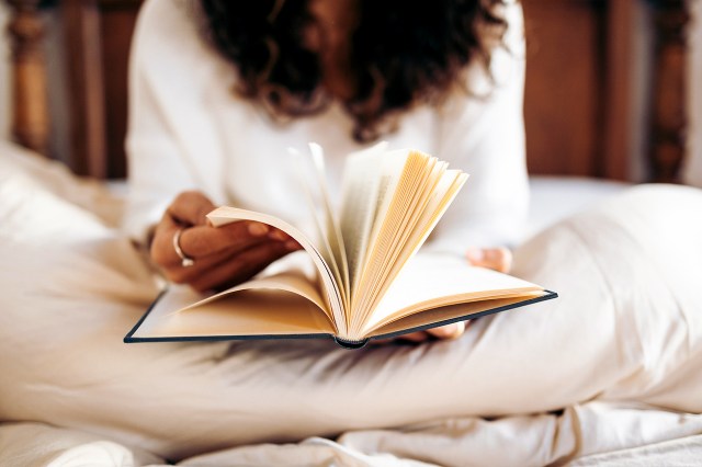 An image of a woman reading a book in bed