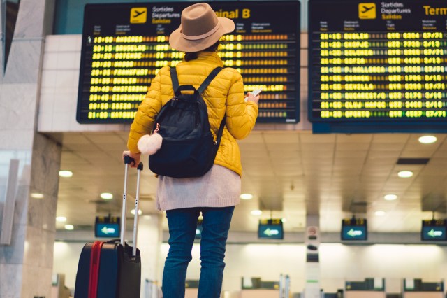 An image of a woman looking a schedule board at an airport