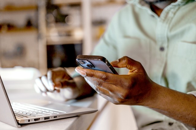 An image of a man on a laptop and his phone