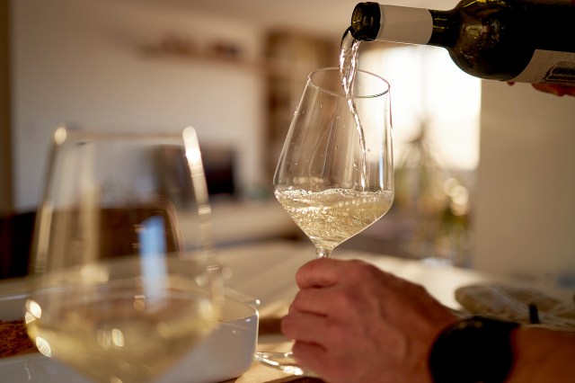 An image of a person pouring a glass of white wine