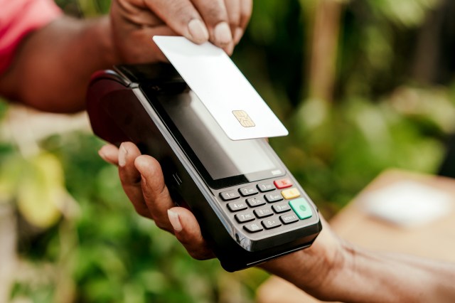 An image of a person tapping a credit card onto a payment machine