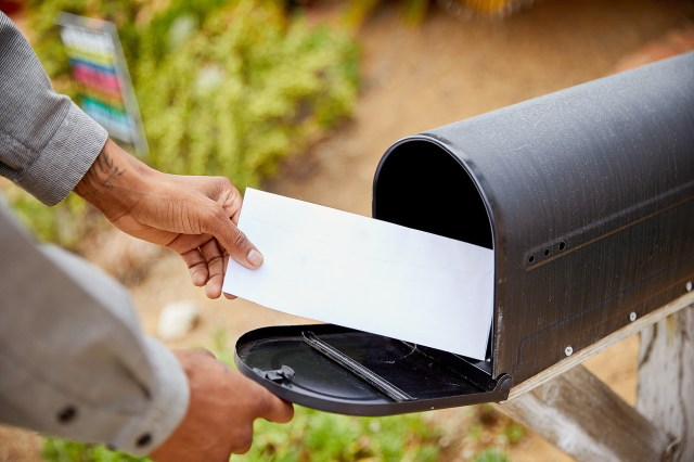 An image of a person putting mail into a mailbox