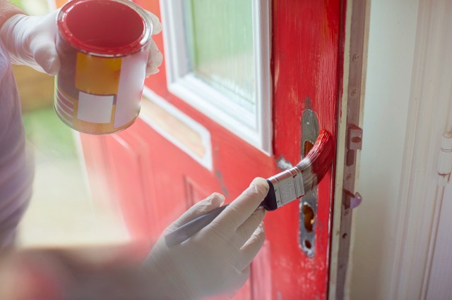 An image of a person painting a door red