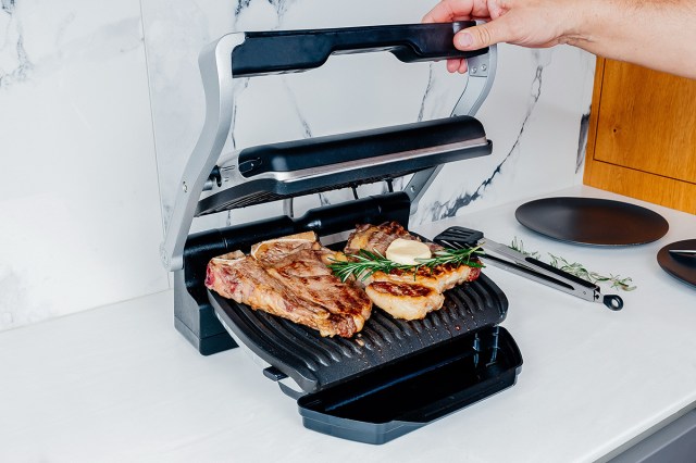 Person cooking steaks on a George Foreman Grill