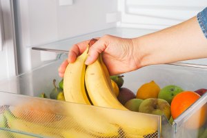 Person placing bananas in a refrigerator bin