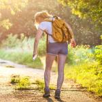 Woman with a backpack spraying bug spray to keep bugs away