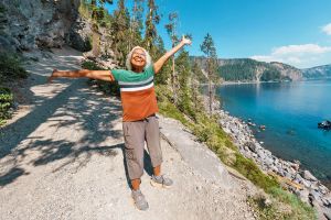 Woman joyfully throwing hands in the air next to a body of water