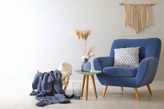 Blue chair next to end table and basket with blankets in it