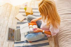 Woman sitting in front of laptop with box of objects open before her