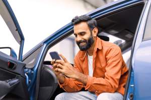Man sitting in car with driver door open while on phone