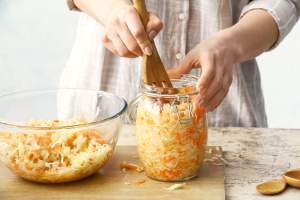 Person making sauerkraut and putting it in a large jar