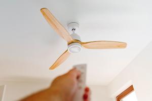 Person holding remote for their ceiling fan and pointing it at the fan