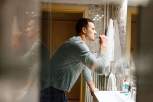 Man brushing teeth over sink