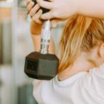 Woman holding a 30-pound weight with both arms behind her head